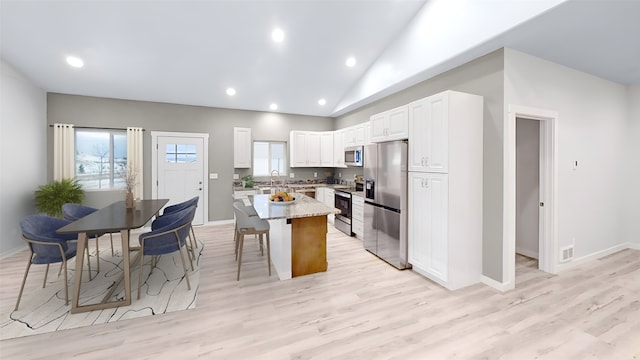 3805 US Highway 93 N, Eureka, MT 59917 - kitchen featuring appliances with stainless steel finishes, a breakfast bar, light stone counters, white cabinetry, and light wood-style floors