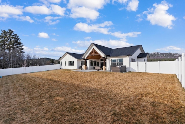 back of property with a patio area, a lawn, a fenced backyard, and a gate
