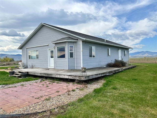 54650 Herak Rd, Charlo, MT 59824 - rear view of house featuring a shingled roof, a deck with mountain view, and a lawn