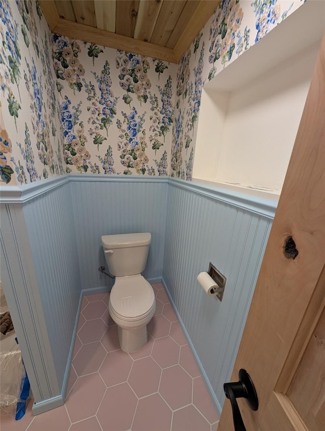 bathroom featuring wallpapered walls, a wainscoted wall, toilet, and tile patterned flooring