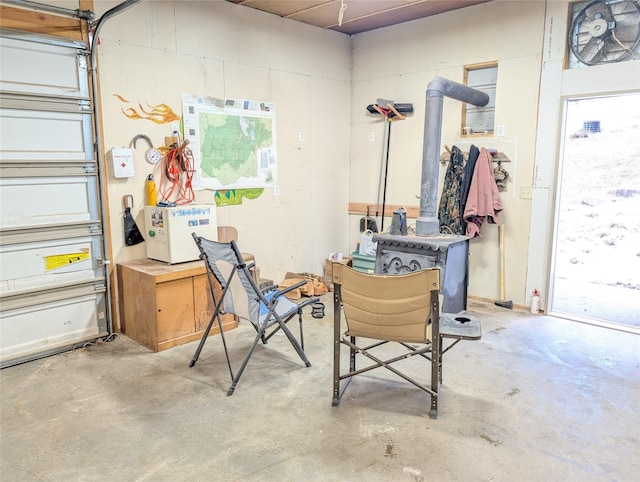 office area featuring unfinished concrete floors and a wood stove