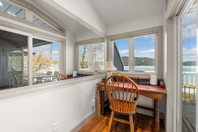 sunroom featuring vaulted ceiling, wood finished floors, and a water view