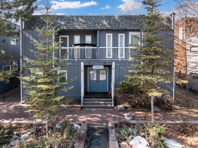 view of front of house with a shingled roof and a balcony