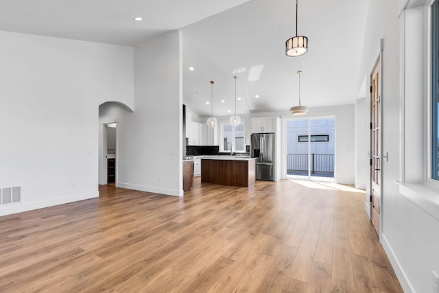 5665 Cattle Dr, Missoula, MT 59808 - kitchen with stainless steel refrigerator with ice dispenser, open floor plan, white cabinets, arched walkways, and a kitchen island