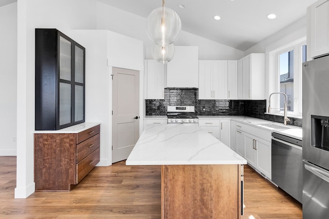 5665 Cattle Dr, Missoula, MT 59808 - kitchen with appliances with stainless steel finishes, a sink, a center island, backsplash, and vaulted ceiling
