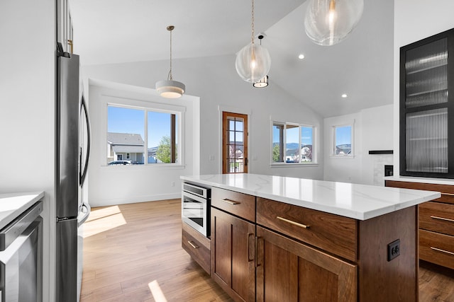 5665 Cattle Dr, Missoula, MT 59808 - kitchen featuring built in microwave, freestanding refrigerator, lofted ceiling, healthy amount of natural light, and light wood-style floors