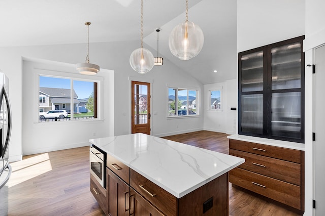 5665 Cattle Dr, Missoula, MT 59808 - kitchen featuring built in microwave, vaulted ceiling, wood finished floors, and plenty of natural light