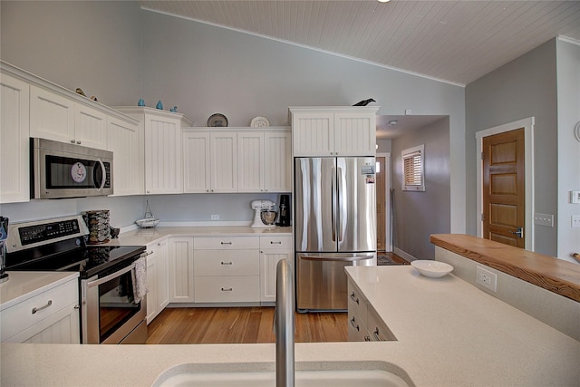 23877 3rd St, Dayton, MT 59914 - kitchen with appliances with stainless steel finishes, vaulted ceiling, light countertops, white cabinets, and ornamental molding