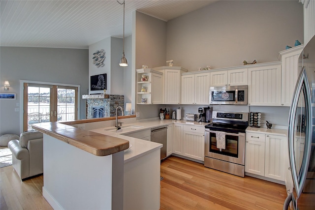 23877 3rd St, Dayton, MT 59914 - kitchen featuring stainless steel appliances, open floor plan, a peninsula, light wood-style flooring, and white cabinets