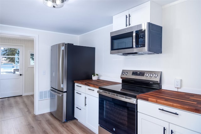 1613 Main Ave, Libby, MT 59923 - kitchen featuring butcher block counters, appliances with stainless steel finishes, light wood-style floors, white cabinets, and baseboards
