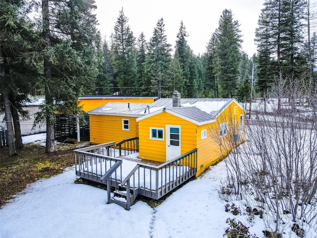 1613 Main Ave, Libby, MT 59923 - snow covered house featuring a standing seam roof, metal roof, a deck, a chimney, and a wooded view