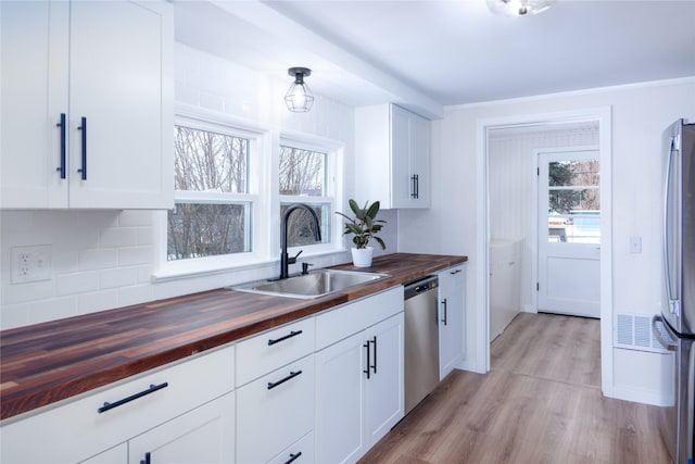 1613 Main Ave, Libby, MT 59923 - kitchen with butcher block countertops, a sink, appliances with stainless steel finishes, light wood finished floors, and decorative backsplash