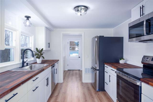 1613 Main Ave, Libby, MT 59923 - kitchen featuring butcher block countertops, stainless steel appliances, a sink, and light wood finished floors