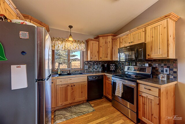 kitchen featuring black appliances, a sink, light wood finished floors, and tasteful backsplash