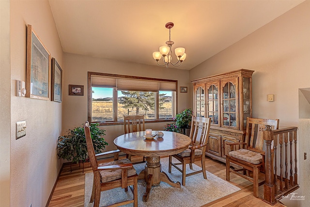 dining room with vaulted ceiling, light wood finished floors, and a chandelier