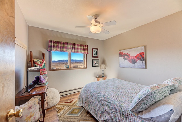 bedroom featuring baseboard heating, wood finished floors, and ceiling fan