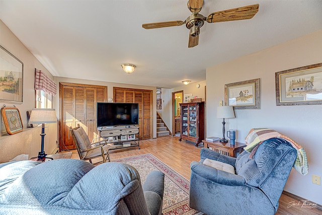 living room featuring stairs, wood finished floors, and a ceiling fan