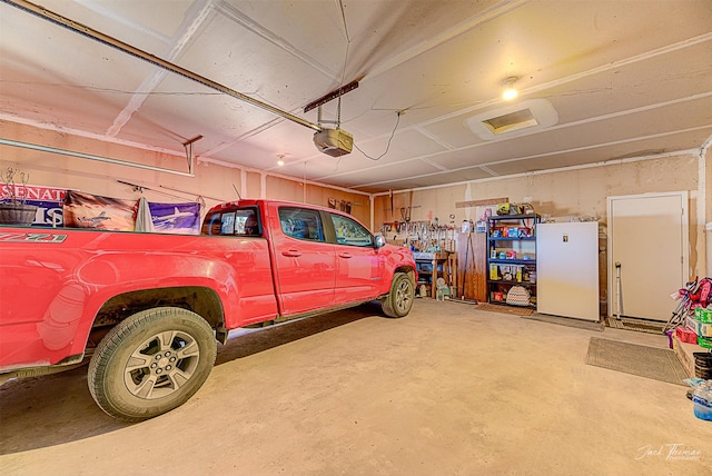 garage featuring freestanding refrigerator and a garage door opener