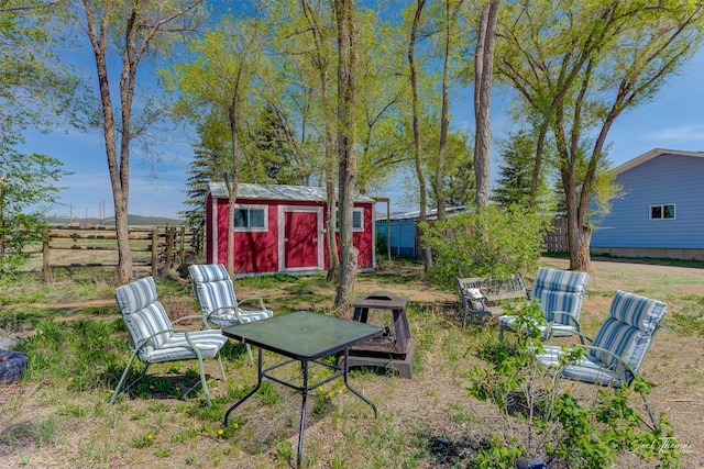 view of yard featuring a storage shed, fence, and an outdoor structure