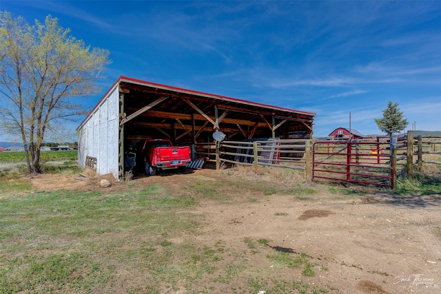 view of outbuilding with a detached carport, an outdoor structure, and fence