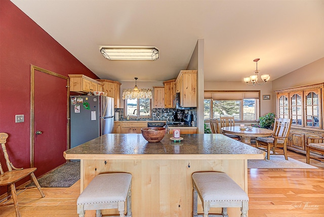 kitchen with a chandelier, freestanding refrigerator, lofted ceiling, light wood-type flooring, and healthy amount of natural light