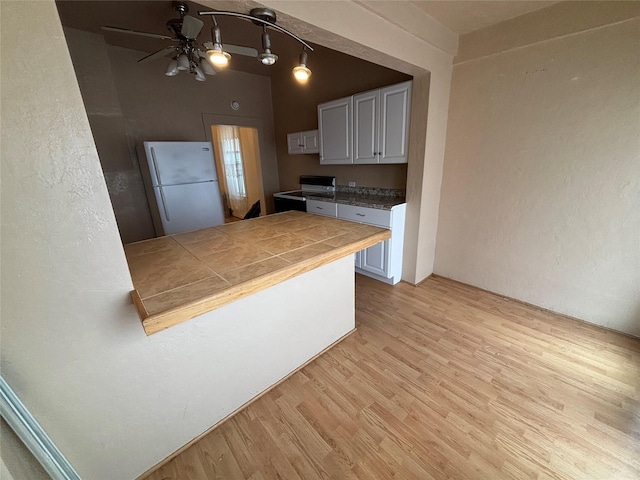 1022 Lewisohn St, Butte, MT 59701 - kitchen with freestanding refrigerator, electric range oven, light wood-style flooring, a ceiling fan, and tile counters
