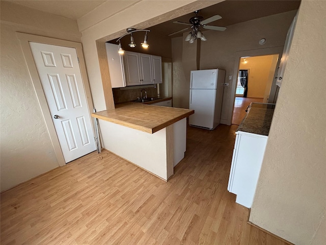 1022 Lewisohn St, Butte, MT 59701 - kitchen with freestanding refrigerator, washer / dryer, a ceiling fan, light wood-style floors, and a peninsula