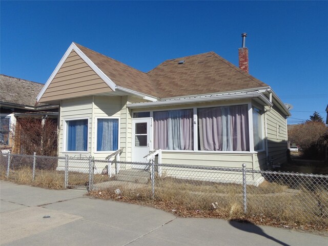 bungalow-style house with a fenced front yard and a chimney