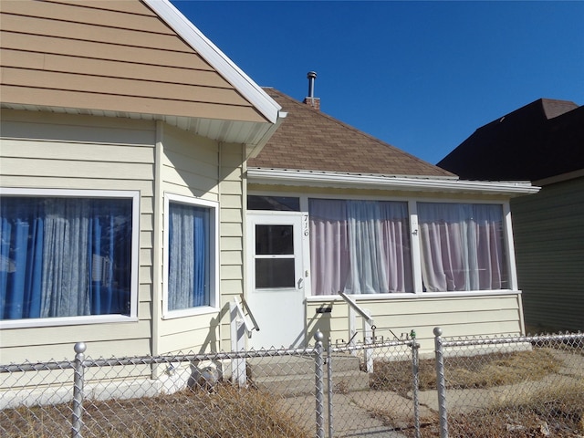 view of property exterior featuring a fenced front yard and a shingled roof