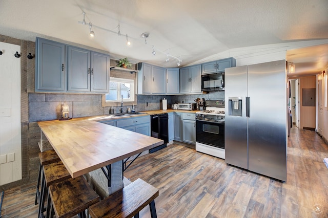 2931 Melrose Rd, Helena, MT 59602 - kitchen with black appliances, a sink, lofted ceiling, wood finished floors, and tasteful backsplash