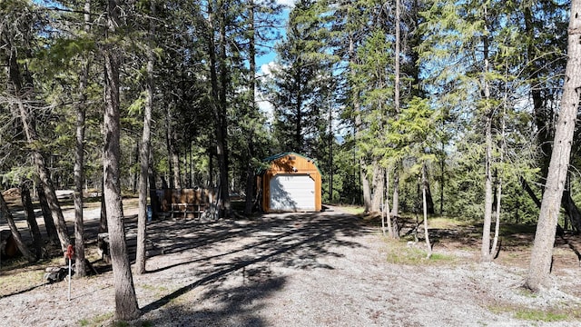 421 Cherry Creek Rd, Thompson Falls, MT 59873 - view of yard featuring an outdoor structure, dirt driveway, a wooded view, and a garage