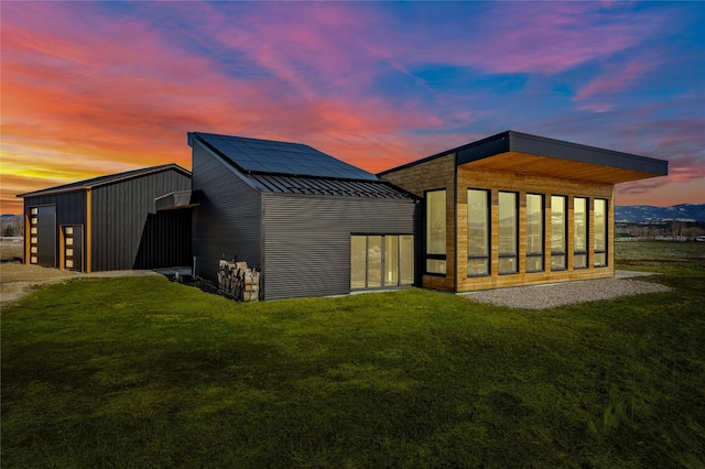 5052 Hoblitt Ln N, Florence, MT 59833 - back of house at dusk featuring a lawn, a standing seam roof, and metal roof