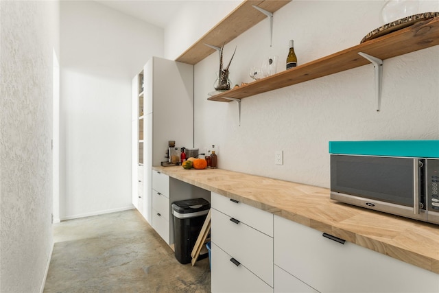 5052 Hoblitt Ln N, Florence, MT 59833 - kitchen with stainless steel microwave, open shelves, wooden counters, white cabinets, and concrete flooring