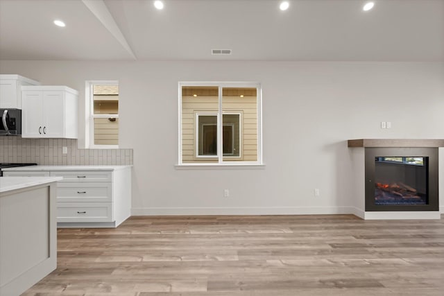 1048 Mill Creek Dr, Bigfork, MT 59911 - kitchen featuring stainless steel microwave, white cabinetry, light countertops, backsplash, and baseboards