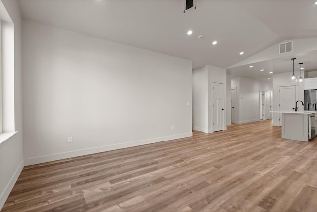 1048 Mill Creek Dr, Bigfork, MT 59911 - unfurnished living room with lofted ceiling, light wood-style flooring, baseboards, and recessed lighting