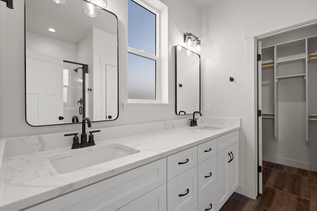 1048 Mill Creek Dr, Bigfork, MT 59911 - full bathroom featuring double vanity, a spacious closet, wood finished floors, and a shower