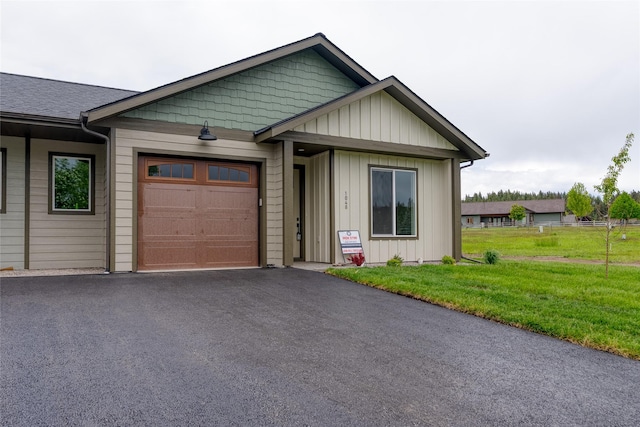 1048 Mill Creek Dr, Bigfork, MT 59911 - view of front facade featuring an attached garage, a front yard, asphalt driveway, and board and batten siding