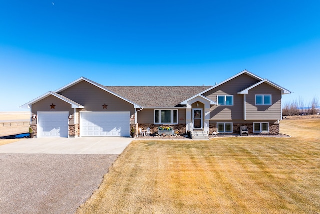 tri-level home with a garage, stone siding, concrete driveway, and a front lawn