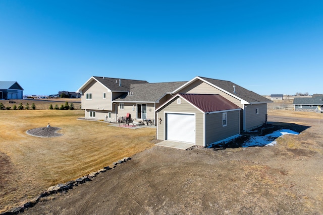 view of front of property with an attached garage, a front lawn, an outbuilding, driveway, and a patio