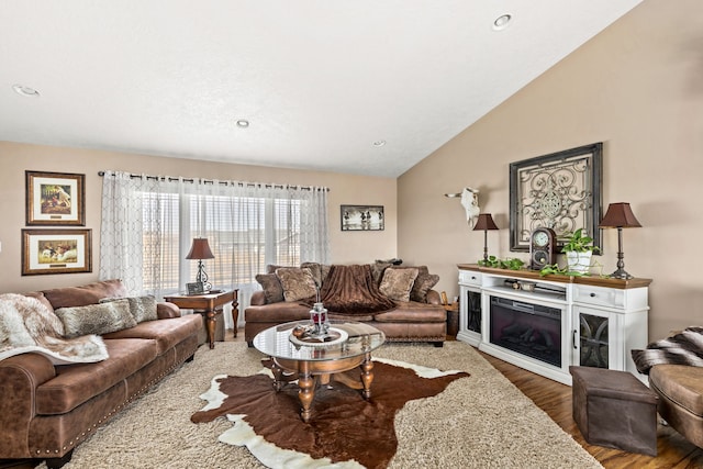 living room with a glass covered fireplace, vaulted ceiling, recessed lighting, and wood finished floors