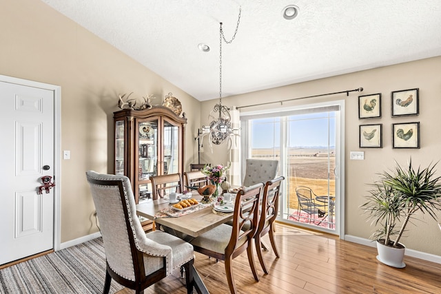 dining room featuring an inviting chandelier, a textured ceiling, baseboards, and light wood-style floors
