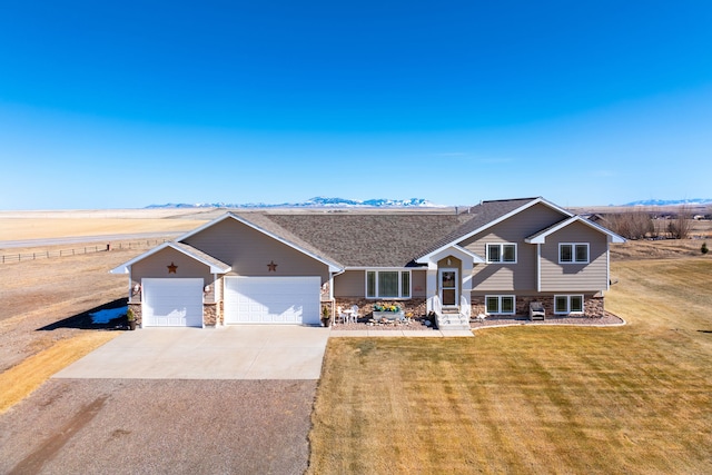 split level home with a front lawn, concrete driveway, a garage, stone siding, and a mountain view