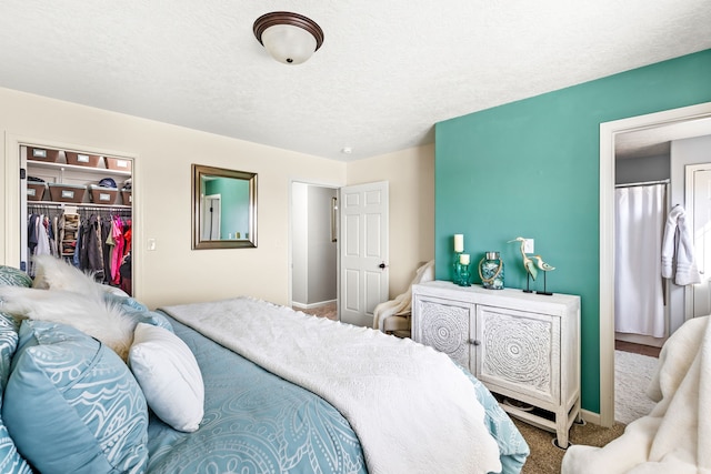 carpeted bedroom featuring a spacious closet, baseboards, a closet, and a textured ceiling
