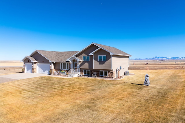 split level home featuring a garage, stone siding, a front lawn, and driveway