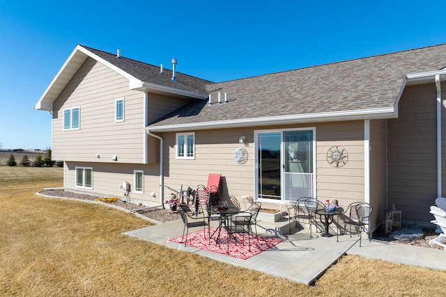 back of house with a yard, roof with shingles, and a patio area