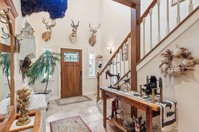 entryway featuring baseboards, light tile patterned floors, and stairway