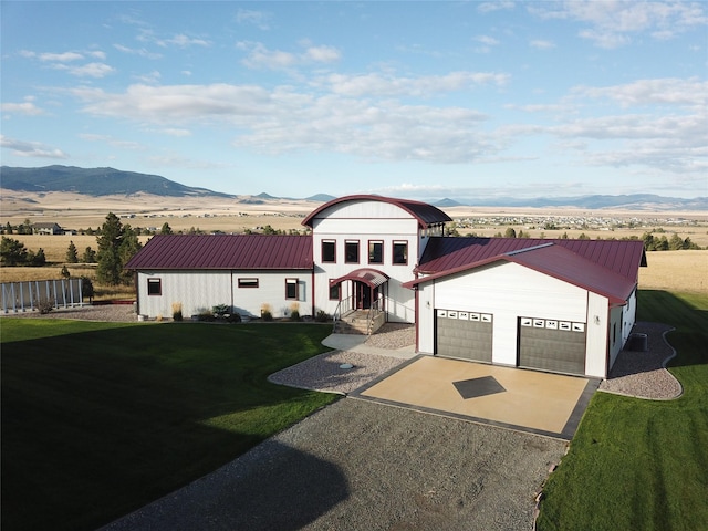 view of front of house featuring a front lawn, driveway, a mountain view, an attached garage, and metal roof