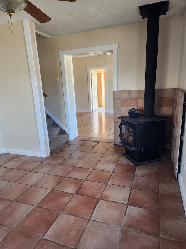 406 W 1st St W, Whitehall, MT 59759 - interior space featuring a wood stove, stairway, baseboards, and ceiling fan