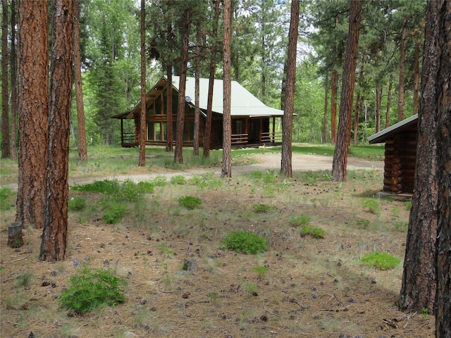 807 Pheasant Run, Hamilton, MT 59840 - view of front facade featuring log siding, an outbuilding, an exterior structure, and a forest view