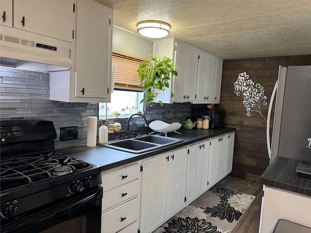 7884 Challis Ln, Missoula, MT 59808 - kitchen with black gas stove, under cabinet range hood, freestanding refrigerator, white cabinetry, and dark countertops